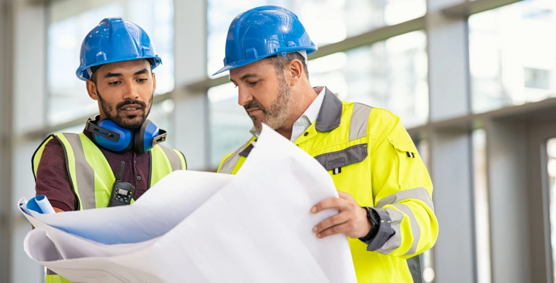 Engineers in hard hats examining plans